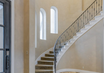 Curved staircase with iron bannister and high ceiling