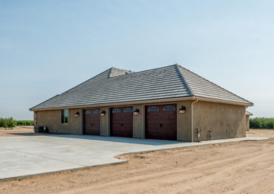 Back of newly constructed home, showing garage doors and dirt lot