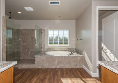 Bathroom showing tub and glass shower with window over looking yard