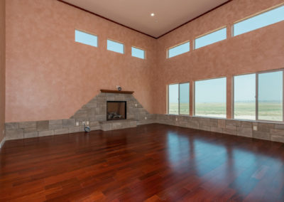 Stone fireplace in newly constructed home with wood floor and windows