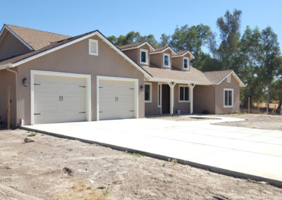 Newly constructed grey home with garage and driveway
