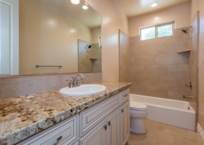 Tan bathroom with granite countertop and stone tile