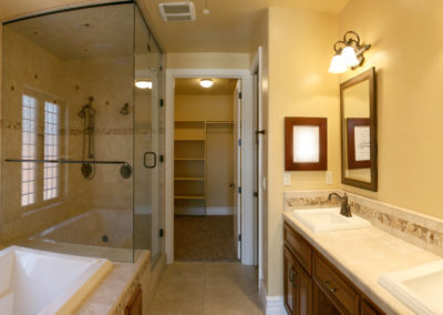 Bathroom with glass shower and double sinks, yellow walls