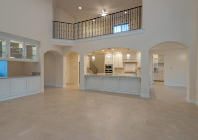 Inside of newly constructed home, looking at upstairs banister and kitchen