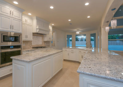 Open area white kitchen with double oven and island