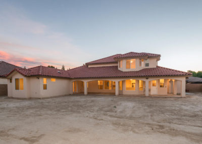 Spanish style beige home with clay roofing shingles at dusk