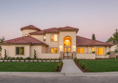 Spanish style beige home with clay roofing shingles at dusk