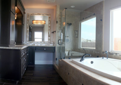 Long shot of bathroom showing bath tub and glass shower enclosure