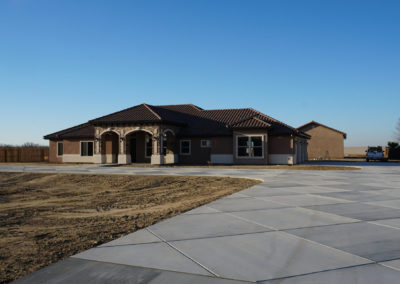 Front of brown home with large slab concrete area