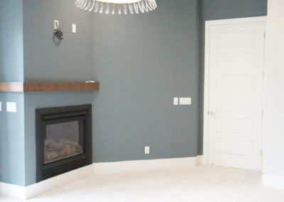 Grey walls and white carpet with a fireplace and chandelier