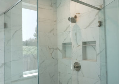 Glass shower and marble walls with built in shelves