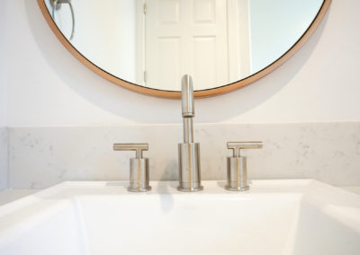 Close up of sink faucet and mirror in white bathroom