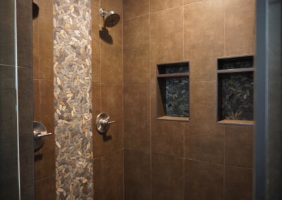 Dark custom shower with built in seat and built in shelves
