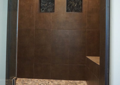 Dark custom shower with built in seat and built in shelves