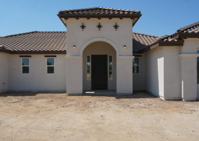 Newly constructed home showing windows, on dirt lot