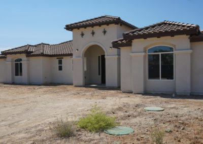 Newly constructed home showing windows, on dirt lot
