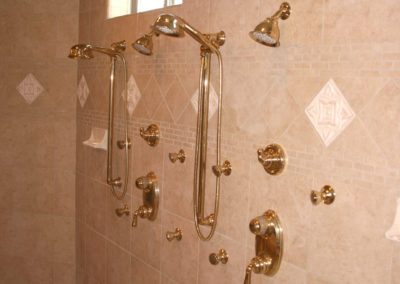 Double shower with tile walls and gold fixtures