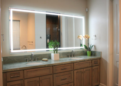 Double sink vanity with stone counter top and lighted mirror