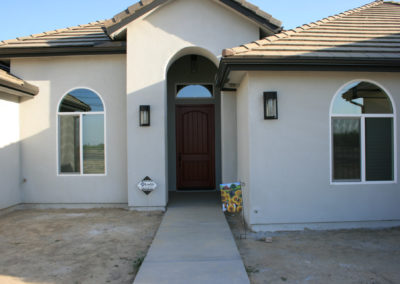 Front view of home's front door with arched windows and a walkway