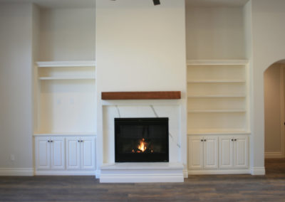 White fireplace with wooden floors and built in cabinets