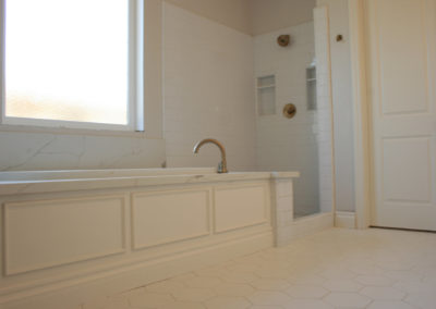 Sunken soaker tub with large widow in white bathroom