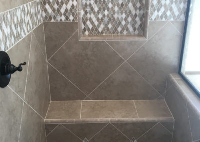 Stone tile shower with built in shelf and seat