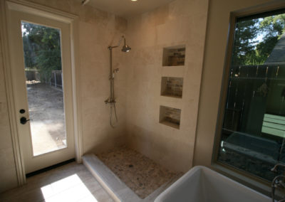 Open shower with built in shelves and glass doorway
