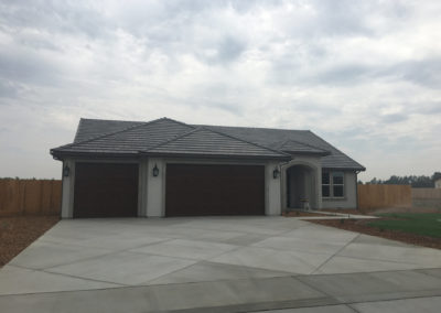 Newly constructed grey home with grass and clouds from the front