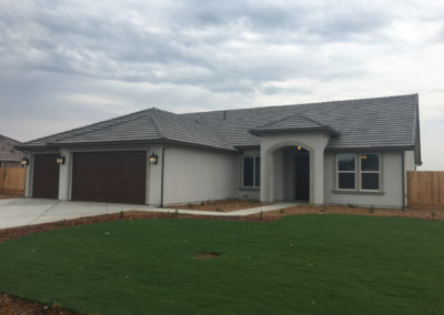 Newly constructed grey home with grass and clouds