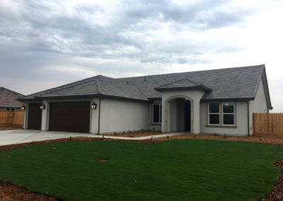 Newly constructed grey home with grass and clouds