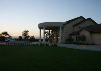 Large home with columns at dusk with car