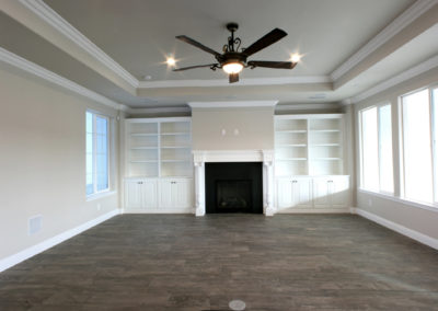 Large fireplace and built in white cabinets and ceiling fan
