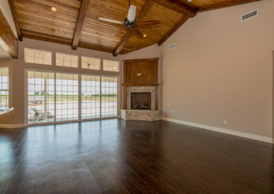 Large room with dark wood floor and stone and oak fireplace