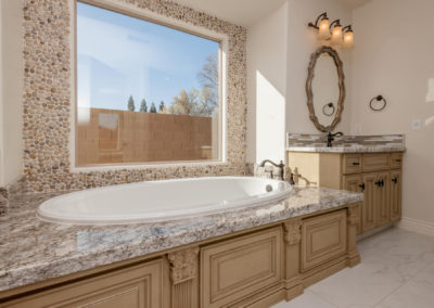 Soaker tub with granite and tumbled stone, large window showing the sky