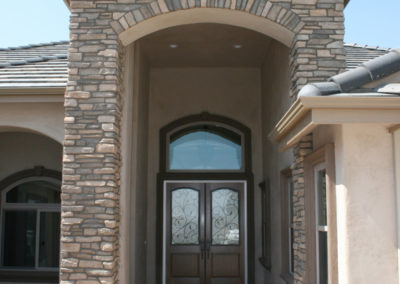 Outside of home facing main entryway with arch and stone