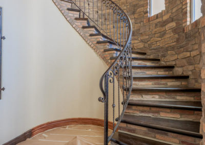 curved stairs with stone wall and tile floor