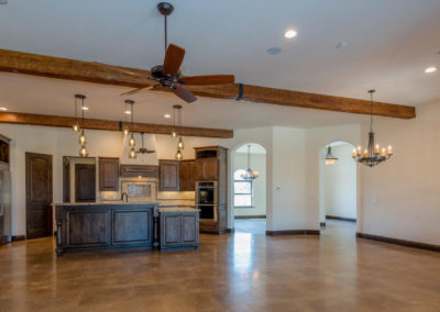Open floor kitchen with exposed beams, unfurnished