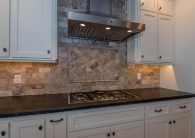 Kitchen stove top with stainless hood and tile backsplash