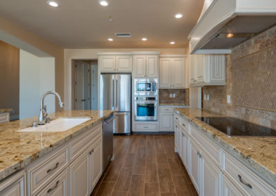 Cream colored kitchen with stainless refrigerator and tile back splash