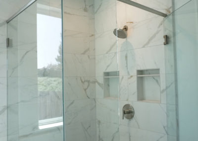 White marble tile shower with glass enclosure