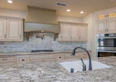 White kitchen with stone backsplash and marble counter top